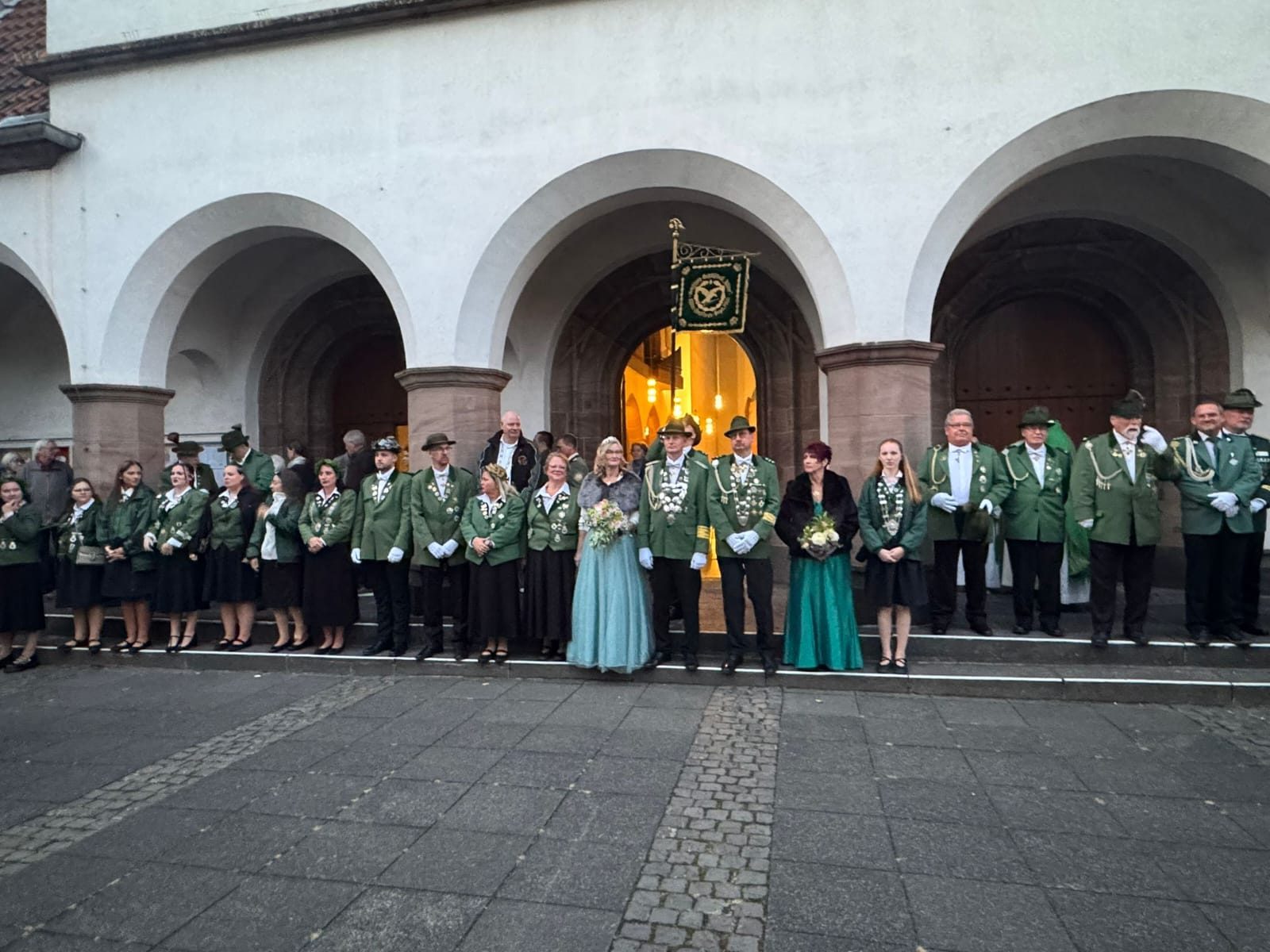 Die Adler-Schützen in grüner Uniform mit dem Königspaar vor der Pfarrkirche St. Pius