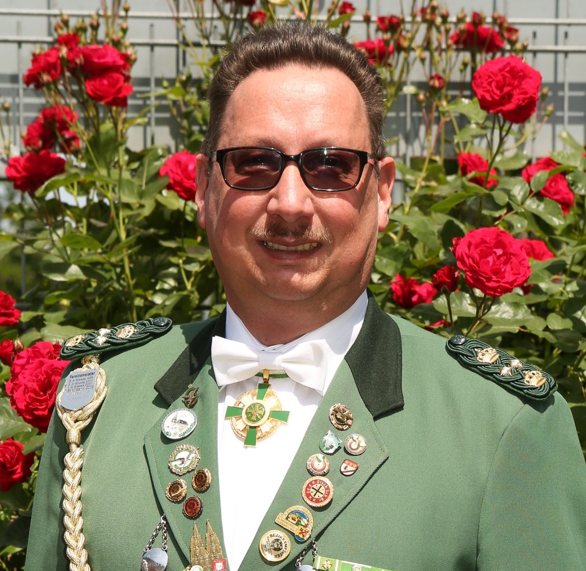 Hans-Jürgen Kampf, 1. Vorsitzender, in Schützenuniform vor roten Rosen